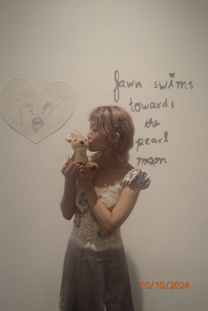 image of Natalee Park kissing a stuffed fawn in front of her show text and poster for fawn swims towards the pearl moon.